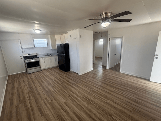 A room with a ceiling fan and wooden flooring.